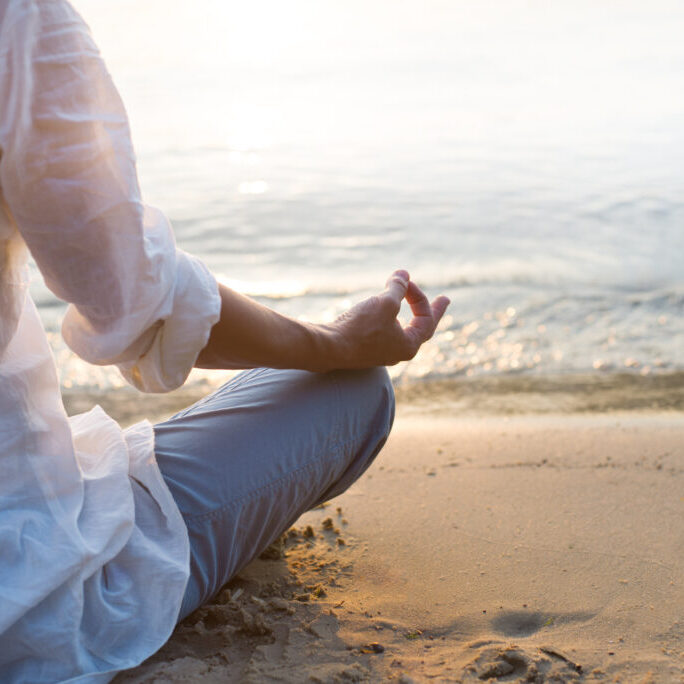 Woman meditating on beach in lotus position